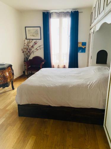 sypialnia z dużym łóżkiem z niebieskimi zasłonami w obiekcie Les Marais w mieście Le Pré-Saint-Gervais