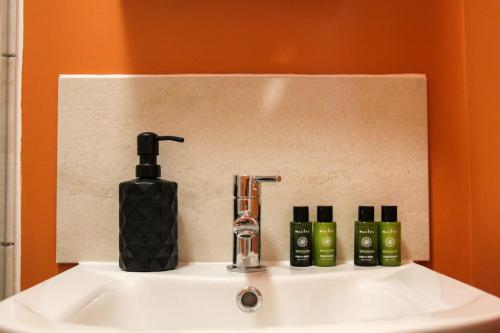 a bathroom sink with a soap dispenser and three bottles at Boutique Studio Apt 10 mins H Potter 17 min London in Watford