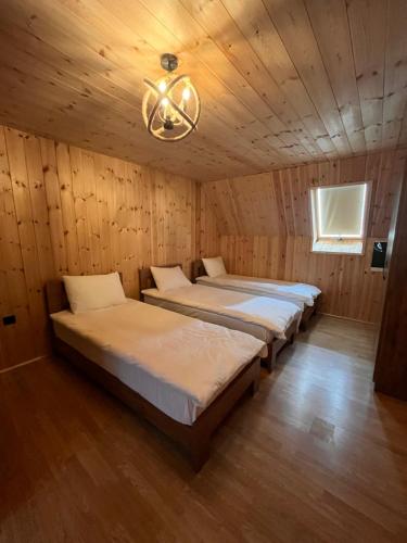 a row of beds in a wooden room with a chandelier at Villa standard n'Bjeshkë in Dragash