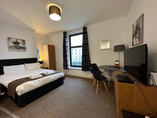 a bedroom with a bed and a desk and a television at The Carlton's Holiday Suites in Bridlington