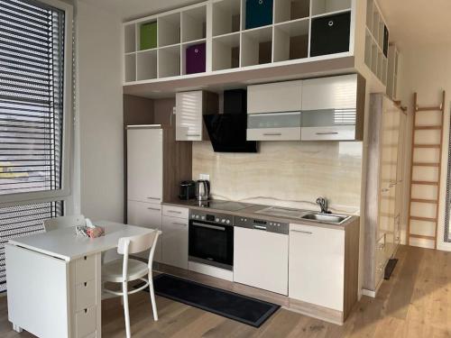 a kitchen with white cabinets and a table with a chair at Le Mont-sur-lausanne: superbe studio ! in Le Mont-sur-Lausanne