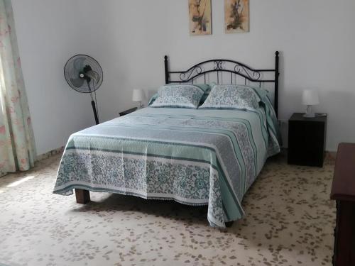 1 dormitorio con 1 cama con edredón verde y ventilador en Casa vacacional en zona céntrica en Conil, en Conil de la Frontera