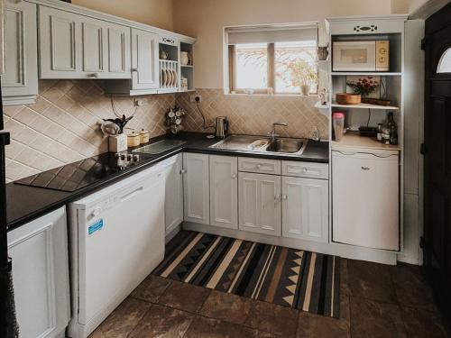 a kitchen with white cabinets and a sink at Dunard house. in Tullaha