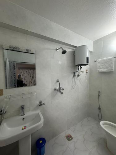 a white bathroom with a sink and a mirror at Boudha Dungkar guest house in Kathmandu
