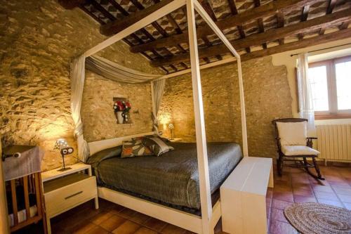 - une chambre avec un lit à baldaquin dans un mur en pierre dans l'établissement Mas Llagostera, à Bisbal del Penedès