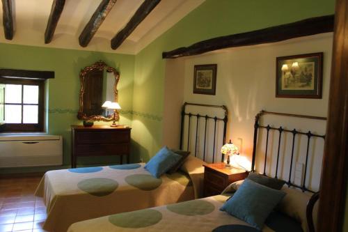 a bedroom with two beds and a mirror at Cal Forner in Santa Oliva