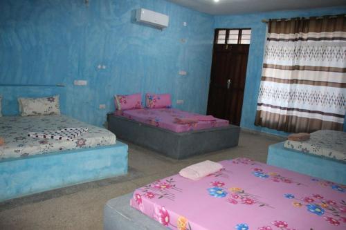 two beds in a room with blue walls at Mbuyuni Lodge Nungwi in Nungwi