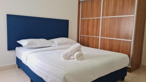 Bett mit blauem Kopfteil sowie weißer Bettwäsche und Kissen in der Unterkunft Alanis Suite KLIA 2Bedroom With Airport Shuttle in Sepang