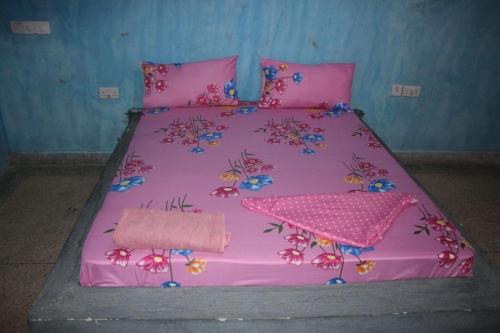 a pink bed with a pink bedspread with flowers on it at Mbuyuni Lodge Nungwi in Nungwi