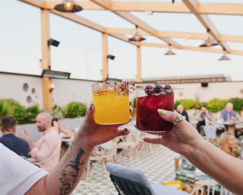 two people holding up drinks in their hands at The Hoxton, Shoreditch in London