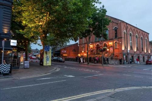a city street with a large brick building on the corner at Beautiful Apartment in the city center in Belfast