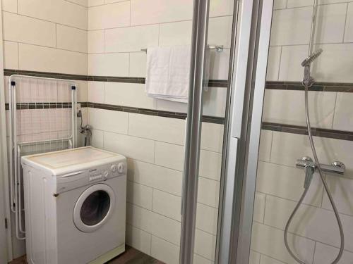 uma casa de banho com uma máquina de lavar roupa e um chuveiro em Proche Lausanne: Studio bien équipé em Prilly