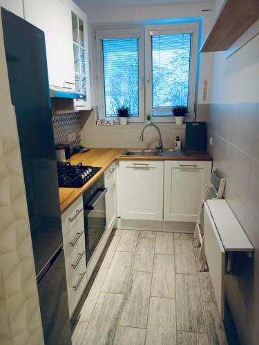 a kitchen with white cabinets and a sink and two windows at ClickTheFlat Miła Center Apart Rooms in Warsaw