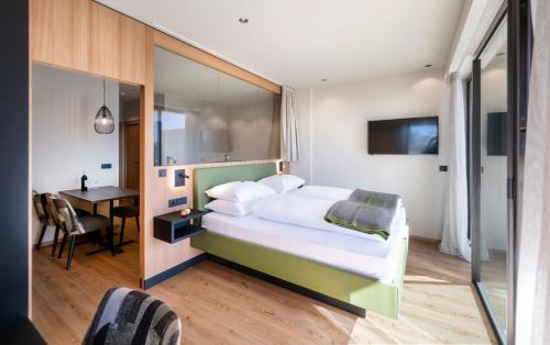 a bedroom with a large bed and a desk at Berghotel Schlemmer in Bressanone