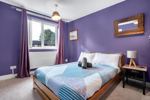 Dormitorio púrpura con cama y ventana en Emma's Central House & Parking en Nottingham