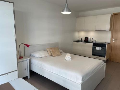 ein kleines Schlafzimmer mit einem weißen Bett und einer Küche in der Unterkunft Joli studio confortable ! in Prilly