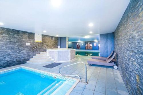 una piscina en una habitación con una pared de ladrillo en Suite Retreat Luxury Apartment, en Penruddock