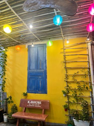 a yellow wall with a blue door and a bench at K-HOUSE Homesaty Phan Thiết in Ấp Bình Hưng