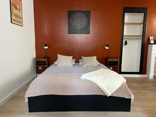 a bedroom with a large bed with orange walls at L’Etape, cœur de ville in La Charité-sur-Loire
