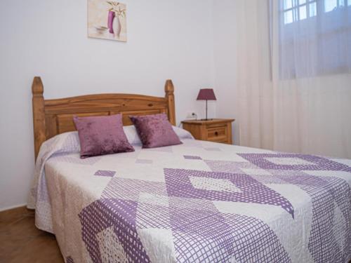 Cama morada y blanca con almohadas moradas en un dormitorio en Casa con Terraza Privada cerca del Pueblo para familias A, en Conil de la Frontera