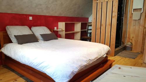 a bedroom with a large bed with a red wall at Maison au sommet des montagnes in Boussenac