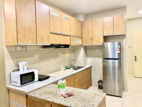 a kitchen with wooden cabinets and a stainless steel refrigerator at Deco Home @ Imago The Loft in Kota Kinabalu