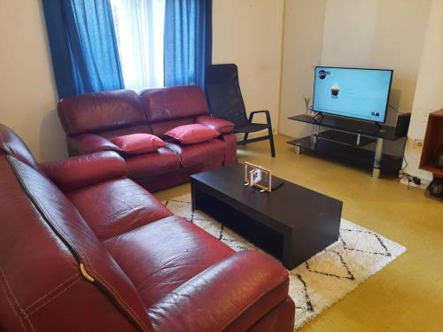 sala de estar con sofá de cuero y TV en Chambre meublée, en Poissy