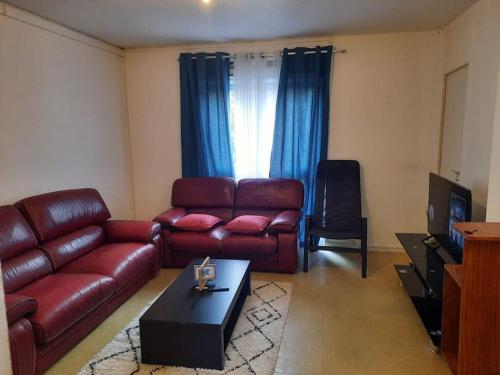sala de estar con sofá de cuero y TV en Chambre meublée, en Poissy