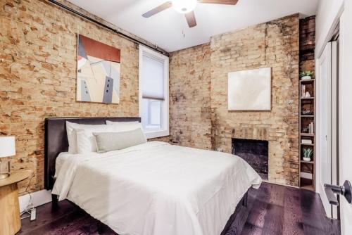 Dormitorio con paredes de ladrillo, cama y chimenea en Artist Gallery Downtown 2Bed 2Bath Condo en Cincinnati