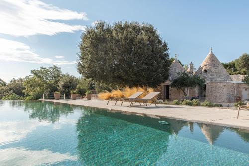 a swimming pool with two chairs next to a house at Trulli Mest'Andrea alle lame in Noci