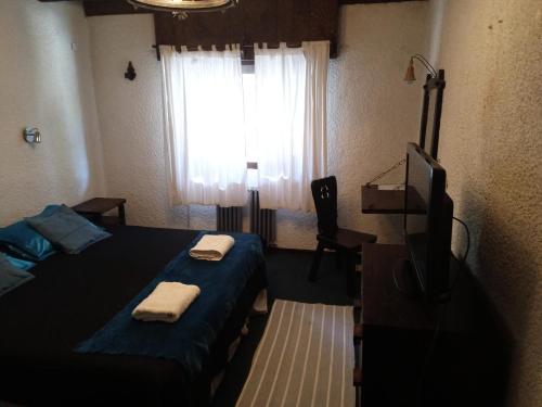 a bedroom with a bed and a television and a window at El Molino in San Carlos de Bariloche