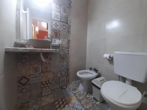 y baño con aseo, lavabo y espejo. en San Remo Viking Hotel en Pinamar