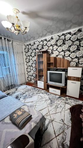 Cette chambre comprend un lit et une télévision. dans l'établissement Чистая и уютная квартира в 6-ом микрорайоне, à Taraz