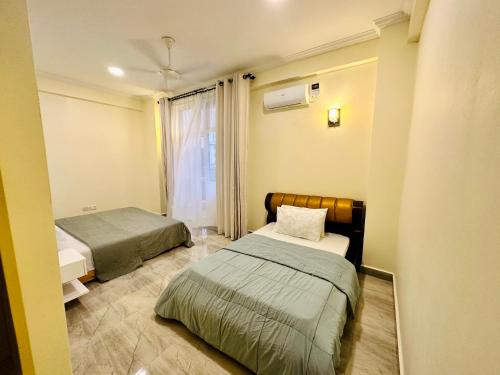 a small room with two beds and a window at SEA-VIEW 3-Bedroom/5-BEDS-APT in Dar es Salaam