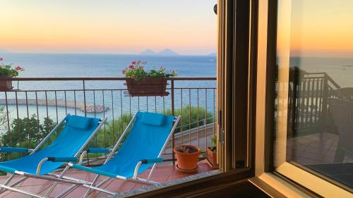 2 sedie blu su un balcone con vista sull'oceano di Perla d'Orlando a Capo dʼOrlando