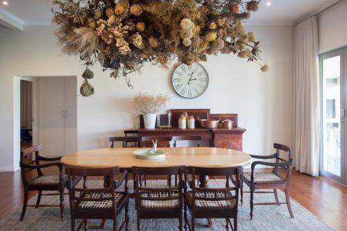 a dining room with a table and a clock on the wall at Fransmanskraal Accommodation - Luxury Stellenbosch Farm Villa in Stellenbosch
