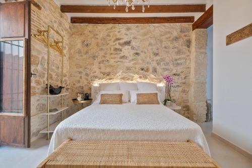 a bedroom with a bed and a stone wall at Ca Sana Teulada Moraira, Grupo Terra de Mar, alojamientos con encanto in Moraira