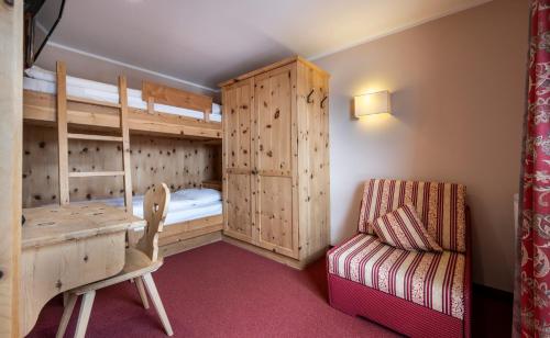 a bedroom with bunk beds and a desk and a chair at Berghotel Schlemmer in Bressanone