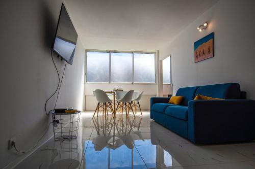 Sibèl Appart في فورت-دو-فرانس: غرفة معيشة مع أريكة زرقاء وطاولة