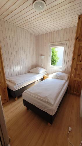 two beds in a room with a window at OW Plaża Klub domki in Dziwnów