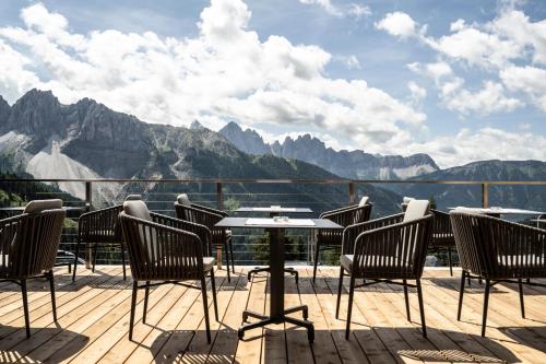 a table and chairs on a deck with a view of mountains at Berghotel Schlemmer in Bressanone