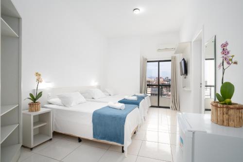 a white bedroom with a bed and a balcony at Boulevard Central Canasvieiras Hotel in Florianópolis