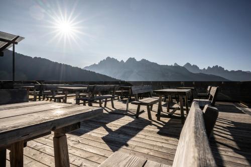 a row of tables and benches on a wooden deck at Berghotel Schlemmer in Bressanone