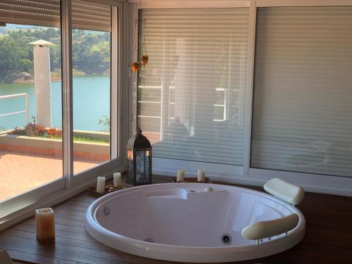 a large white bath tub in a room with windows at Casa na represa in Vargem