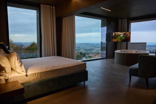 1 dormitorio con cama, bañera y ventanas grandes en Le Agavi Resort & SPA, en Saludecio