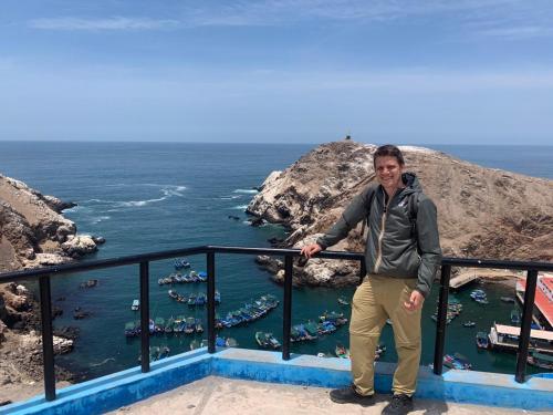 un uomo in piedi su un balcone con vista sull'oceano di Qaleta Azul a Camaná