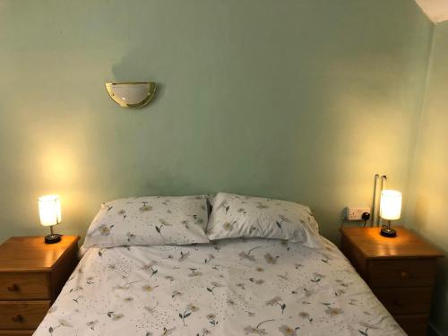 a bedroom with a bed with two nightstands and two lamps at Double Room in Character Cottage With Parking, Beaulieu, New Forest in Beaulieu