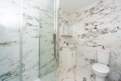 a bathroom with a toilet and a glass shower at Modern One Bed Flat Lowestoft in Lowestoft