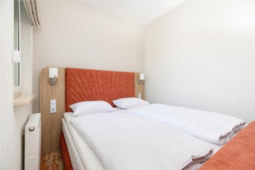 a bedroom with two beds with white sheets and an orange headboard at Rent like home - Bel Mare F527 in Międzyzdroje