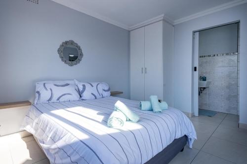 a white bedroom with a large bed with blue sheets at De Bakke Terrace 26 in Mossel Bay